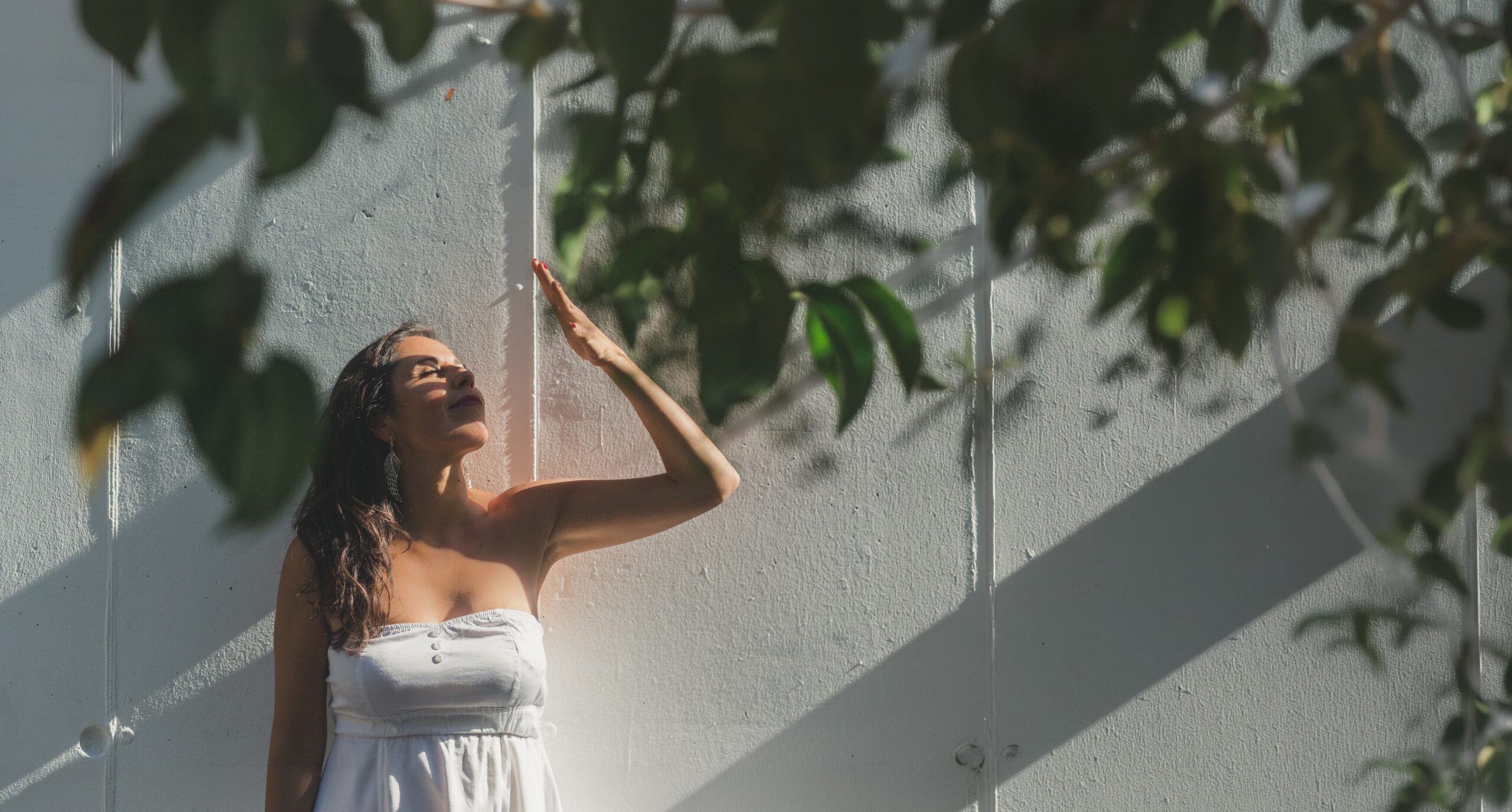 Marcela Moreno, terapeuta holística online, junto a un muro iluminado por el sol